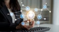 Businesswoman holding light bulb with technology icons representing innovation, cloud computing, data connectivity, and Royalty Free Stock Photo