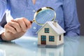 Businesswoman Holding Magnifying Glass Over House Model Royalty Free Stock Photo