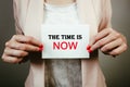 Businesswoman holding note with text the time is now. Opportunity, urgency, deadline concept Royalty Free Stock Photo
