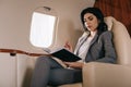 Businesswoman holding pen while looking at notebook in private jet Royalty Free Stock Photo