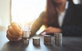 Businesswoman holding and putting lightbulb on coins stack on table Royalty Free Stock Photo