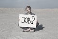 Businesswoman holding a sign in search of work. Financial crisis. Unemployment. A man in a business suit in the desert.