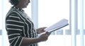 Businesswoman holding and turning pages of a file in hand