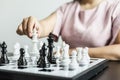 Businesswoman holding white chess pieces on a chessboard, comparing chessboard to business administration.