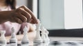 Businesswoman holding white chess pieces on a chessboard, comparing chessboard to business administration.