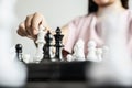 Businesswoman holding white chess pieces on a chessboard, comparing chessboard to business administration.