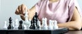 Businesswoman holding white chess pieces on a chessboard, comparing chessboard to business administration.