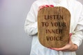 Businesswoman holding wooden board with inspirational advice - listen to your inner voice