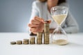 Businesswoman With Hourglass And Stack Of Coins