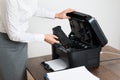 Businesswoman Inserting Laser Cartridge In Printer