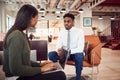 Businesswoman Interviewing Male Job Candidate In Seating Area Of Modern Office Royalty Free Stock Photo