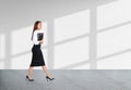 Businesswoman with journal in hands, walking on grey concrete fl