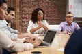 Businesswoman Leading Office Meeting Of Colleagues Sitting Around Table