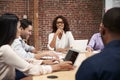 Businesswoman Leading Office Meeting Of Colleagues Sitting Around Table