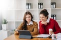 Businesswoman leading team meeting and using tablet and laptop computer with financial in coworking office