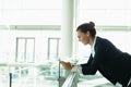 Businesswoman leaning on railing and using mobile phone in a modern office building Royalty Free Stock Photo