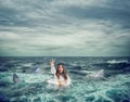 Businesswoman with lifebelt surrounded by sharks asks help Royalty Free Stock Photo