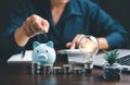 Businesswoman with lightbulb and piggy bank and using calculator to calculate and money stack. Save energy and money with