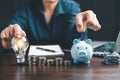 Businesswoman with lightbulb and piggy bank and using calculator to calculate and money stack. Save energy and money with