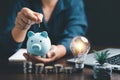 Businesswoman with lightbulb and piggy bank and using calculator to calculate and money stack. Save energy and money with