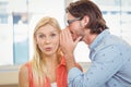 Businesswoman listening to rumor which male colleague is whispering Royalty Free Stock Photo