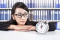 Businesswoman looking at alarm clock