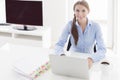 Businesswoman looking bored in front of laptop and television