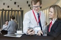 Businesswoman looking at colleague using smart phone during coffee break at convention center Royalty Free Stock Photo