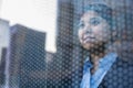 Businesswoman looking out through window, reflection of the city on the glass