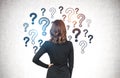 Businesswoman looking at question marks on wall Royalty Free Stock Photo