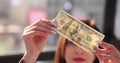 Businesswoman looks at banknote to check authenticity