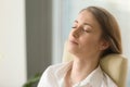 Businesswoman lying on back chair with closed eyes