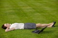 Businesswoman lying in park with laptop