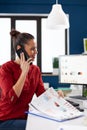 Businesswoman making a call using smartphone sitting at desk