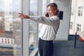 Businesswoman Making Phone Call Standing By Office Window and showing view from above Royalty Free Stock Photo