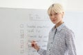 Businesswoman marks completed tasks from list on whiteboard