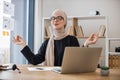 Businesswoman meditating in office chair behind computer