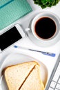 Businesswoman morning with coffee, sandwich, mobile on white table background top view