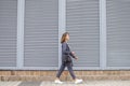 Businesswoman in the morning goes to work in the city against the background of the wall, a girl in a striped suit walks along the