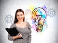 Businesswoman with notebook in hands with colourful light bulb and gears Royalty Free Stock Photo