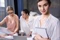 Businesswoman with notebook in hands looking at camera