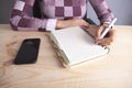 Businesswoman notebook pen smartphone on wooden background