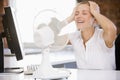 Businesswoman in office with computer and fan