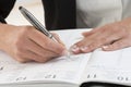 Businesswoman in office noting an appointment in her diary