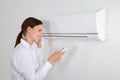 Businesswoman Operating Air Conditioner Royalty Free Stock Photo