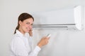 Businesswoman Operating Air Conditioner Royalty Free Stock Photo