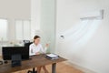 Businesswoman Operating Air Conditioner In Office