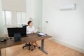 Businesswoman Operating Air Conditioner In Office Royalty Free Stock Photo