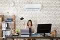 Businesswoman Operating Air Conditioner Royalty Free Stock Photo