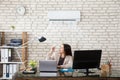 Businesswoman Operating Air Conditioner Royalty Free Stock Photo